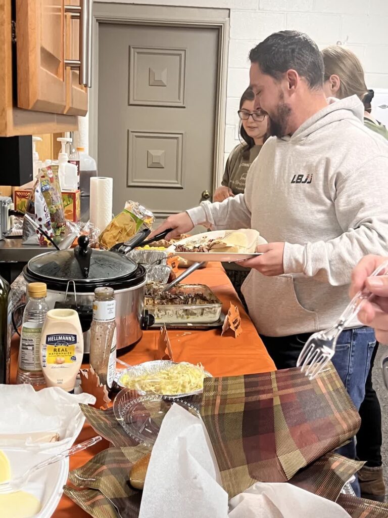 Food layed out on the table people making plates to eat for friendsgiving