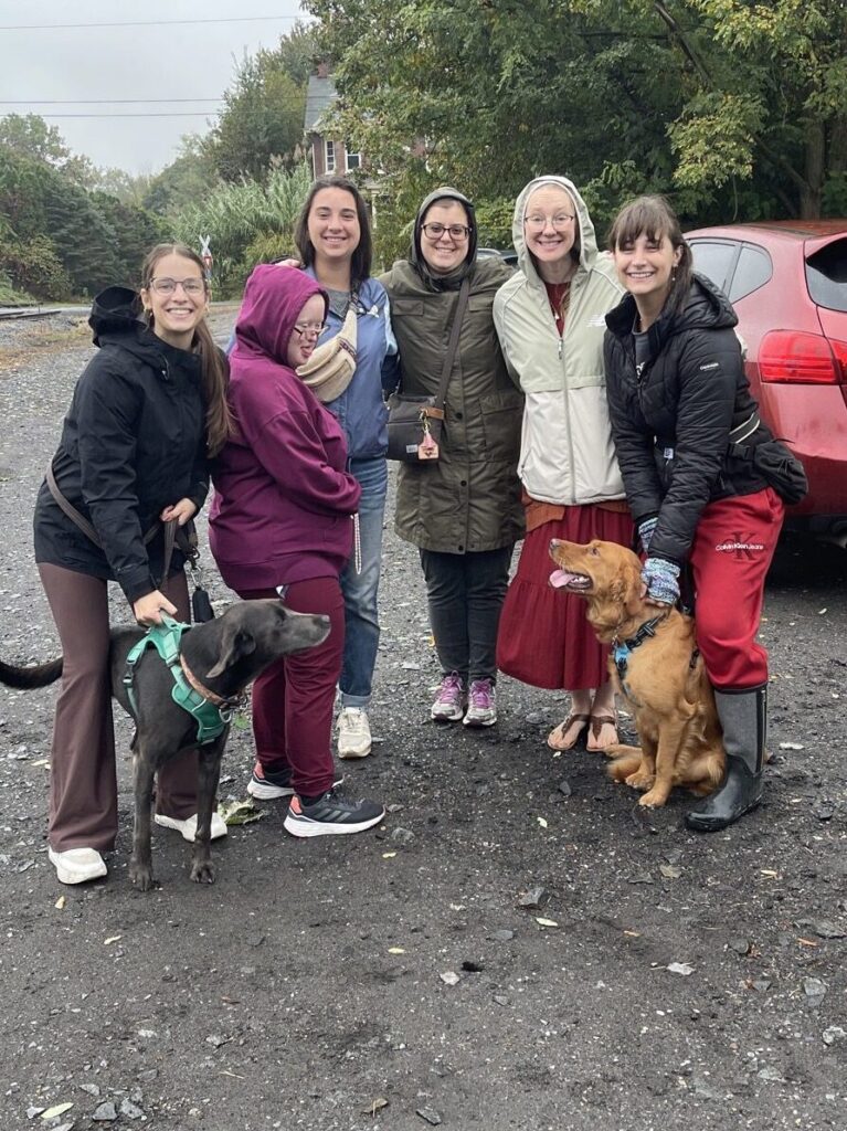 Group of young women and two dogs ready to talk and pray the rosary in the rain